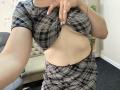 OliviaGranda lifting her plaid shirt, exposing her bare tits and flat, pale belly. She's wearing a matching plaid skirt, with one hand on her chest.