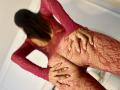 ZammySanz wearing red lace fishnet lingerie, grabbing her ass with both hands, showing her pussy through the net. Her hands have long, red-painted nails.
