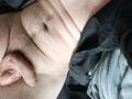 OrianaAndFriends' bare, hairy, pale-skinned torso with a flaccid, circumcised penis and visible navel, lying on dark and gray fabric.