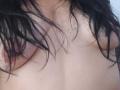 ZarayFeet's bare chest with black, wet, wavy hair covering her small tits and visible areolas. Her pale skin contrasts with the dark hair.