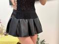 Rorria's black mesh top with tiny white dots and a black lace waistband, paired with a short black leather skirt, showing her upper thighs and part of her ass.