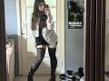 Mettis with long brown hair, white shirt, black mini skirt, thigh-high socks, and black boots, taking a mirror selfie, showing her ass in a mirror reflection.