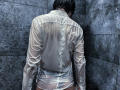 RubyMote's wet, white shirt clings to her back, showing her ass through the transparent fabric. Her dark hair is wet, and she's leaning against gray, textured tiles.