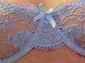 Blue lace bra with floral patterns and a small blue ribbon on FrenchShanna's tits, showing her creamy skin. The lace is semi-transparent, highlighting her cleavage.