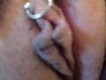 FrenchShanna's hand is spreading her slightly blurry, brown-skinned pussy with fingers, showing her shaved, pink, inner labia and a silver ring on her finger.