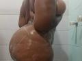 ViaraMoon is showering, her wet, dark brown ass glistening with soap suds, her back and butt prominently displayed, hands behind her, water droplets on her skin.