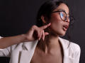 JennTylor with dark hair, glasses, and white shirt, pointing with her finger, lips slightly parted, showing her sexy tits and ass through the open shirt.