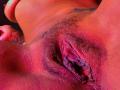 LorenLuv's purple-hued pussy with visible labia and a small patch of dark pubic hair. Her tattoo is partially visible on the right. Her skin has a red tint.