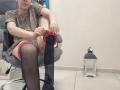 JoannaSia sitting in a chair, pulling up a black stocking on her right leg, wearing a leopard print dress and red underwear, with a lantern on the floor.