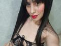 MadissonFontaine with long black hair, red lipstick, black lace top, showing her small tits, light skin, and a cute red mole on her right cheek, smiling at the camera.