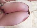 Il sedere chiaro e formoso di AlesadraJoness, in un abito color crema ricamato con fiori, che mostra tatuaggi sull'interno coscia e una collana d'oro con un ciondolo a forma di cuore..