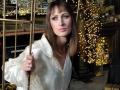 MiraMixi has straight brown hair, blue eyes, and wears a shiny white satin blouse. She holds a golden pole, with sparkling lights in the background.
