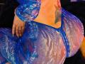 Kkole's big ass in a blue, see-through, mesh dress with purple and pink patterns. Her tattooed right side shows a colorful heart. Her hand rests on her butt.