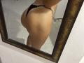 SandraSwweet's ass in black thong reflected in a mirror. Her butt is round and she's wearing a thin strap that's barely covering her. Her skin is tan.