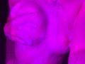 LianaKisses' wet, purple-lit tits are visible, with her right hand partially covering her left breast. Her nipples are slightly erect and there's water on her chest.