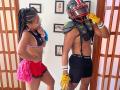 LilithAndAsmodeo, dark-skinned woman with braids, small tits, wearing pink cheerleader skirt, black sports bra, and red pom-poms, stands next to LilithAndAsmodeo in football gear, yellow gloves.