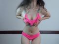 VikkiRi in pink bikini, pulling down top to expose small tits, holding bottom with hands, long brown hair, pale skin, standing, pink panties, slim, subtle belly button.