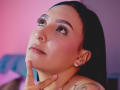SophiieBlair's face, nose pierced, wearing long black hair, blue earrings, ring, tattoo, hand on neck, looking up, pink and purple lighting, makeup with long eyelashes.