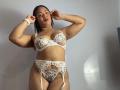 AliceBooty is a curvy woman with light brown skin wearing white lace lingerie, including a bra with flowers, garter, and thong. She has small tits and a visible pussy.