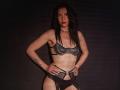 IngaDrein with long dark hair, wearing black lace bra and garter, hands on hips, choker, tattoo on left arm, red lipstick, standing confidently, displaying her tits and ass.