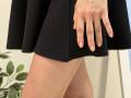 Rorria's hand rests on her black skirt, revealing her bare, tan-skinned thigh. Her fingers are relaxed, showing a slight pinkie. Her skirt is short, exposing her leg.