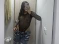 LunnaBlossom indossa una trasparente maglia nera in rete che rivela i suoi piccoli seni e capezzoli, con jeans blu strappati, in piedi in un bagno, mentre scatta un selfie allo specchio..