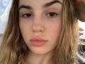 PeacHub69 has light brown, wavy hair, full lips, and a slightly upturned nose. She has brown eyes with long eyelashes, and a small mole on her right cheek.