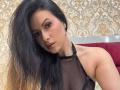 HannaRobertss with long black hair, wearing a black mesh halter top, showing her tits, has pink eyeshadow and brown lipstick, looking at the camera with a serious expression.