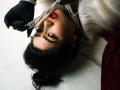 KhloeLawson's face is upside down, holding a string of pearls with black gloves, red lipstick, and dark eyebrows, wearing a white fur and red dress.