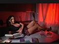 AmelieReea with big tits, lying on kitchen counter, reading book, wearing black top, plaid skirt, high heels, surrounded by books, red light, black hair, sexy, relaxed.