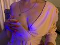 Anshante with pink dress, hand covering her tits, red nails, necklace, blue and purple lighting, her skin is fair, her breasts are visible, her nipples are slightly visible.