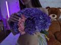 TenerliRize holding a purple and pink hydrangea bouquet, showing her bare tits and a navel piercing, with a brown teddy bear in the background.