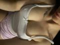 Olieri's boobs in a white, ribbed, spaghetti-strap top, showing cleavage, with pink shorts and a small leaf tattoo on the right side of her chest. Her lips are visible.