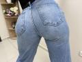 OliviaGranda's denim-clad ass is prominent, showing blue jeans with visible pockets and a slight butt crease. Her black top is barely visible above.