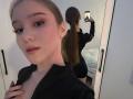 DomingaSierra taking a selfie in a mirror, showing her face and back with her ponytail, wearing a black top, holding a phone, with visible large ass in reflection.