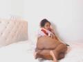 YiyaHot69, curvy with dark brown skin, curly hair, in a white bed, wearing a hoodie, showing her big ass, lying on her side, looking at the camera.