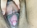 KarlaWild's hairy brown pussy, with her fingers spreading the labia to reveal the pink inner vaginal walls and her clitoral hood. Her hand is on the top left.