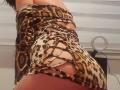 Aiyana's butt in a leopard print, lace-up, tight mini-dress showing her lower back and a bit of her ass. Ring light in the background.