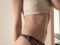 SweetClaraa with a slim, toned body, wearing a beige crop top and grey strappy panties, showing her flat stomach and small, perky tits. Her skin is light and smooth.