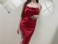Nesie in a red satin dress with lace on the side, showing her ass and holding her hand over her tits, long brown hair, wearing a necklace.
