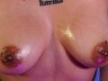 LiMiuu's shiny, large, glistening tits with brown, erect nipples and slightly darker areolas, showing a moist sheen. Her skin is a light brown tone.