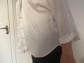 Elliance's white button-up shirt, slightly open, shows black pants and a hint of their ass. The shirt's sleeves are rolled up. Door with metal handle on the left.