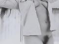 ArianithaXox met een open shirt, waarbij haar borsten zichtbaar zijn, en een donkere, behaarde schaamstreek, met armen omhoog, op een zwart-wit foto. Haar lange haar is gedeeltelijk zichtbaar..