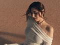 OliviaCluff with dark brown hair, eyes closed, wearing a white off-shoulder top, shadow on her face, black choker, soft sunlight, slightly wet top showing her small tits.