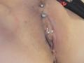 De vagina van FrenchShanna, met een zilveren piercing in de clitorale plooi en een andere in de bovenlip van haar schaamlippen. Haar huid is licht, met wat roodheid rond het gebied..