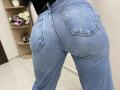 OliviaGranda's ass in tight blue jeans with visible pockets, standing with her back to the camera, showing her butt's shape and texture. Her black top is slightly visible.