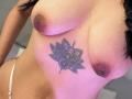 LiaTayloor's topless with large, brown-tipped tits and a purple-hued, floral tattoo between her breasts. She's wearing white, thong-style underwear. Her skin is tan.
