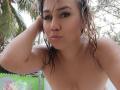 CamilaNoer has wet brown hair, blue eyes, and small boobs. She's topless, with water droplets on her skin, pouting her lips, and resting her hand on her head.