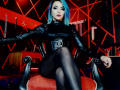 MisssDarkLady with blue hair, wearing a black leather top and pantyhose, sitting on a red chair with legs crossed, black corset, red lipstick, in a dark, sexy room.