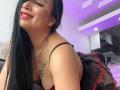 KarimeLeeX with long black hair, red lipstick, and a smile, wearing a black and red sheer dress, showing her tits and a tattoo on her left chest.